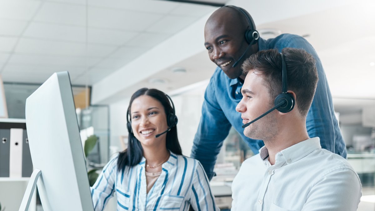 smiling customer service team looking at a computer